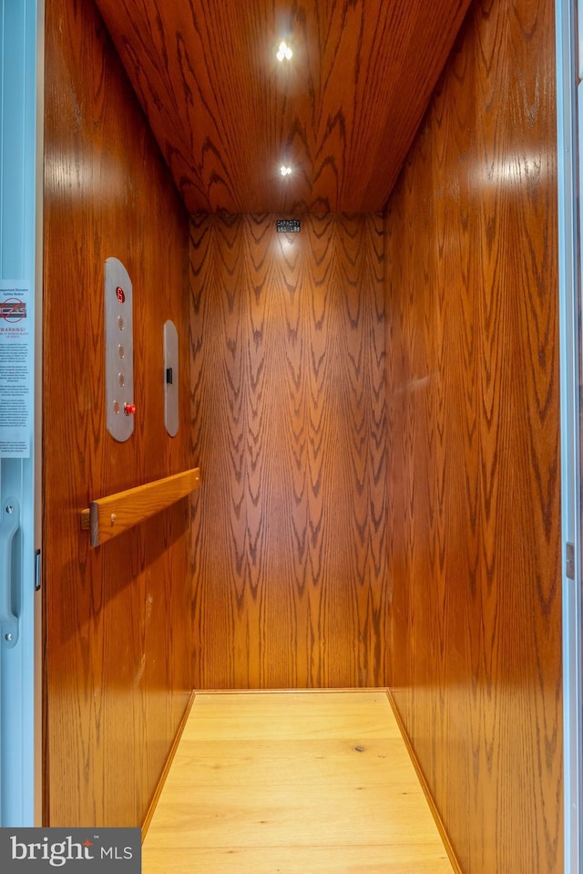 hallway with wooden walls, wood ceiling, and elevator