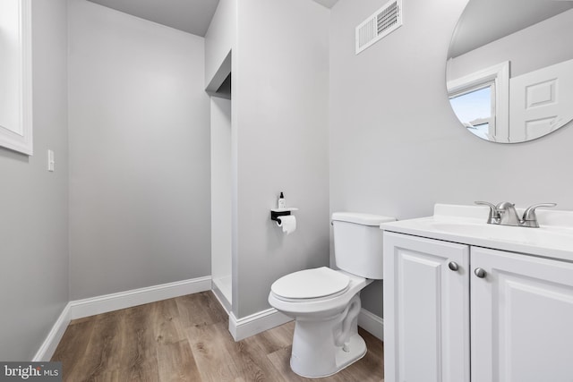 bathroom with toilet, hardwood / wood-style floors, and vanity