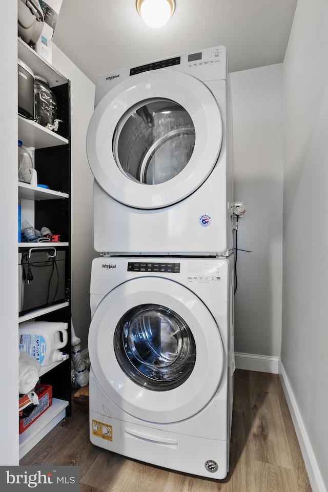 clothes washing area with stacked washing maching and dryer and hardwood / wood-style floors