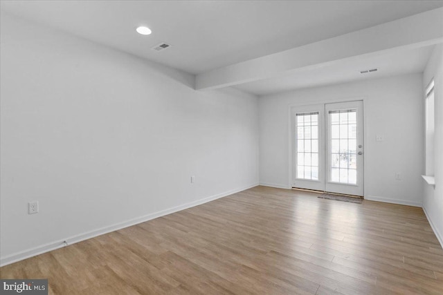 spare room featuring light hardwood / wood-style flooring and beamed ceiling