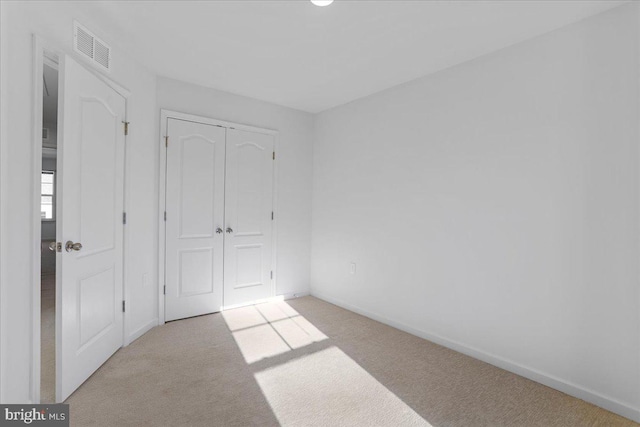 unfurnished bedroom featuring a closet and light colored carpet