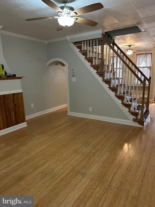 unfurnished living room with ceiling fan, wood-type flooring, and ornamental molding