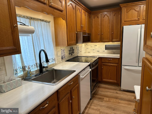 kitchen featuring backsplash, light hardwood / wood-style floors, sink, dishwasher, and white fridge