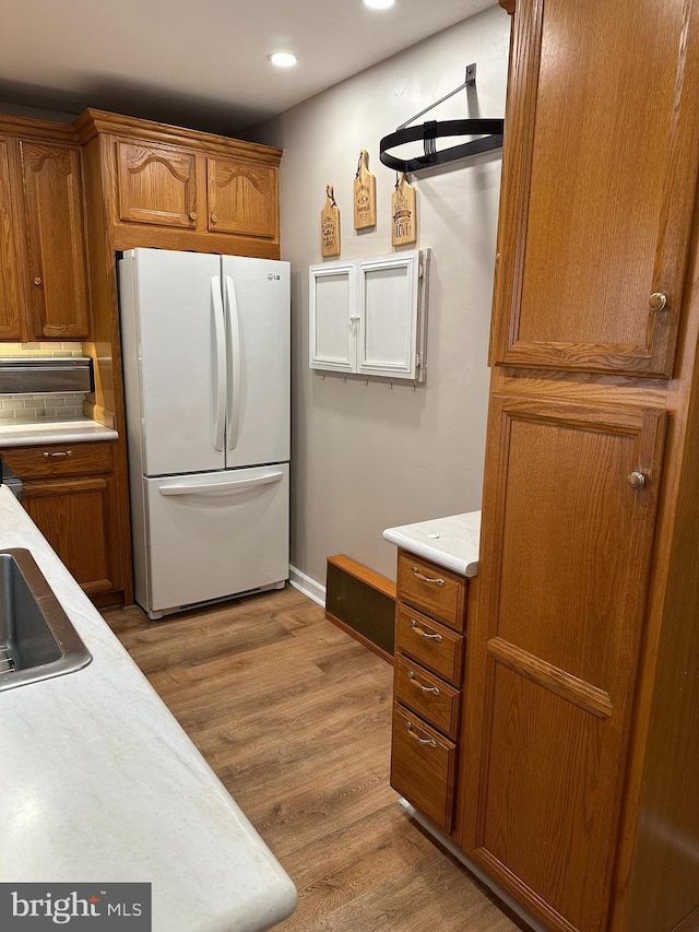 kitchen with white fridge, sink, and light hardwood / wood-style flooring