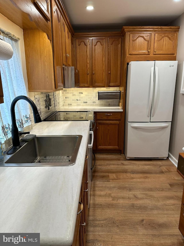 kitchen with backsplash, white refrigerator, sink, and hardwood / wood-style floors