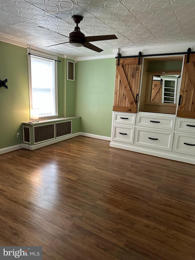 interior space featuring a barn door, ceiling fan, dark hardwood / wood-style flooring, and a textured ceiling