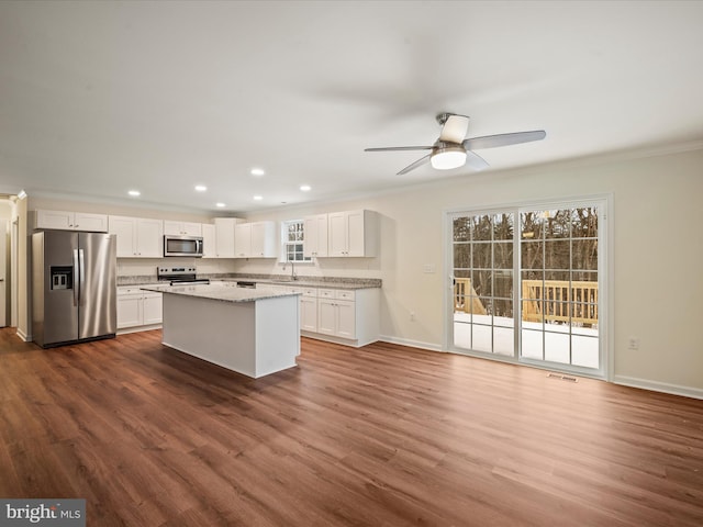 kitchen with appliances with stainless steel finishes, dark hardwood / wood-style floors, white cabinetry, sink, and light stone counters