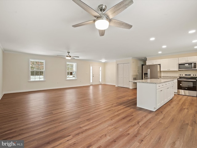 kitchen featuring white cabinetry, a center island, light stone counters, stainless steel appliances, and light hardwood / wood-style flooring