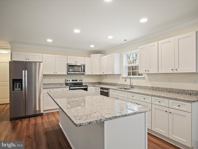 kitchen with a kitchen island, white cabinetry, sink, ornamental molding, and stainless steel appliances