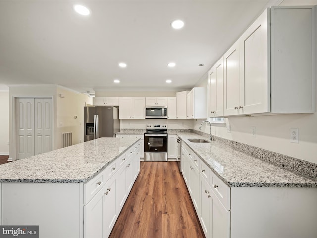 kitchen with sink, appliances with stainless steel finishes, white cabinetry, dark hardwood / wood-style floors, and light stone counters