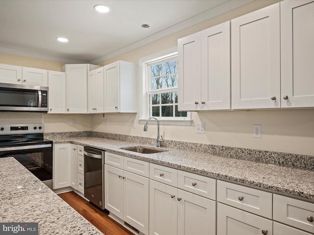 kitchen featuring sink, white cabinetry, crown molding, light stone counters, and appliances with stainless steel finishes