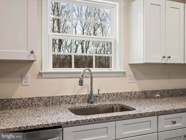 kitchen featuring white cabinetry, light stone countertops, sink, and stainless steel dishwasher