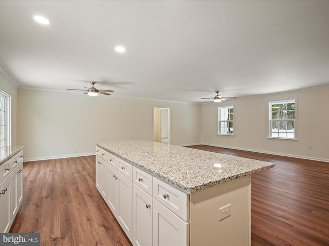 kitchen with ornamental molding, light stone countertops, hardwood / wood-style floors, and white cabinets