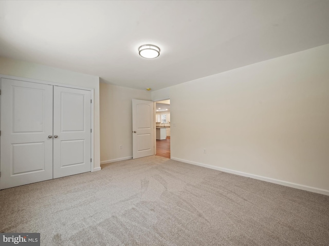 unfurnished bedroom featuring light colored carpet and a closet