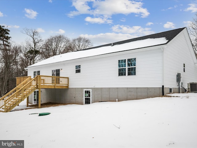 snow covered back of property featuring central AC and a deck