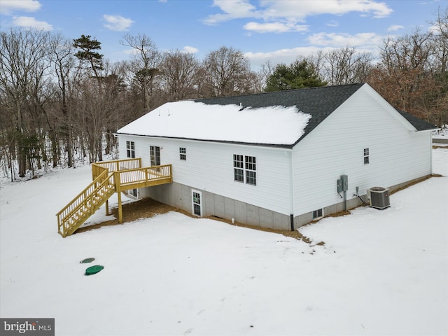 snow covered house with central air condition unit and a deck