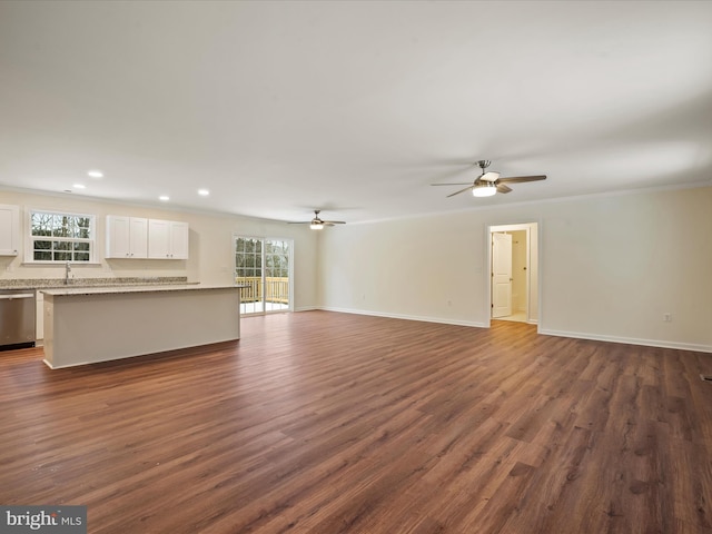 unfurnished living room featuring ornamental molding, dark wood-type flooring, and a wealth of natural light