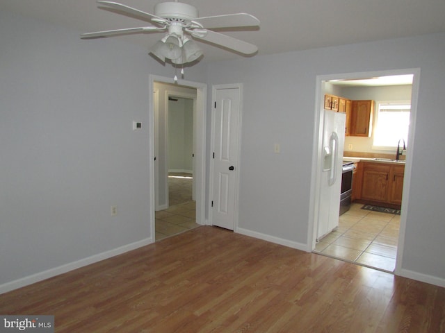 unfurnished room with sink, ceiling fan, and light hardwood / wood-style flooring