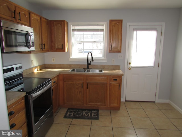 kitchen featuring sink, stainless steel appliances, a healthy amount of sunlight, and light tile patterned flooring