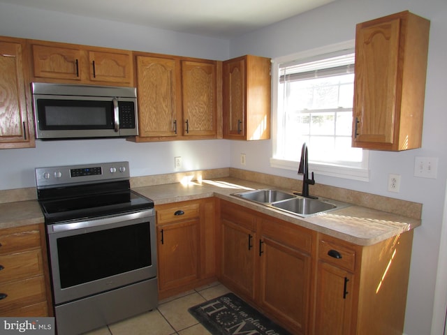 kitchen with appliances with stainless steel finishes, light tile patterned flooring, and sink