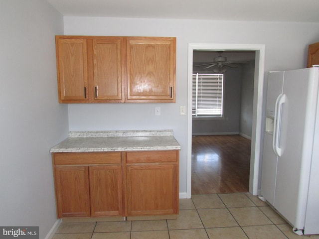 kitchen featuring white refrigerator with ice dispenser, ceiling fan, and light tile patterned floors