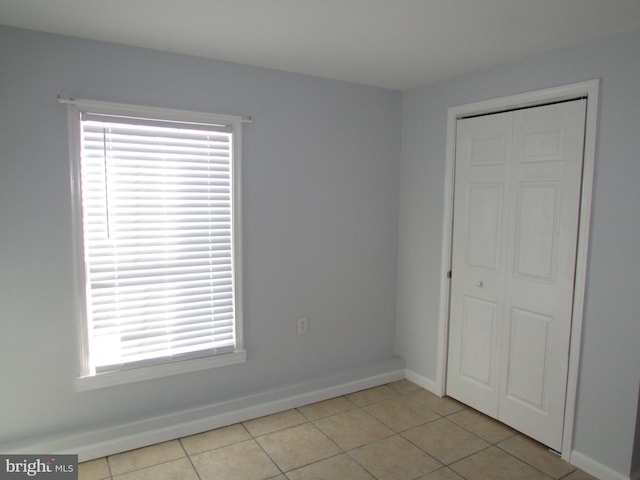 unfurnished bedroom with a closet, light tile patterned floors, and multiple windows