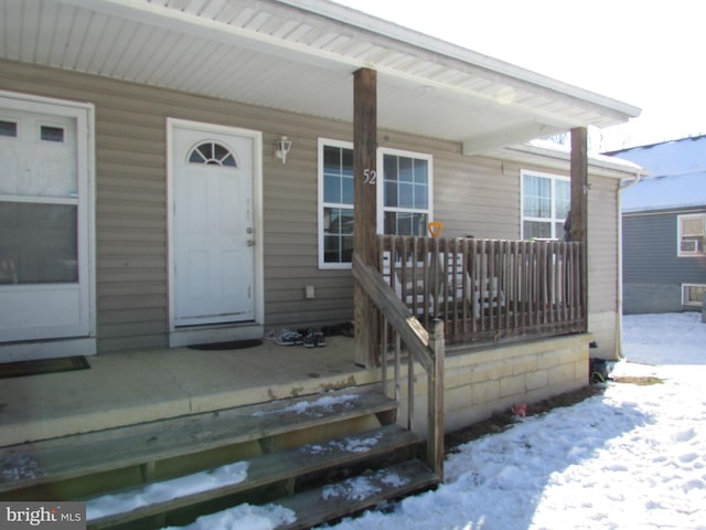 snow covered property entrance with a porch