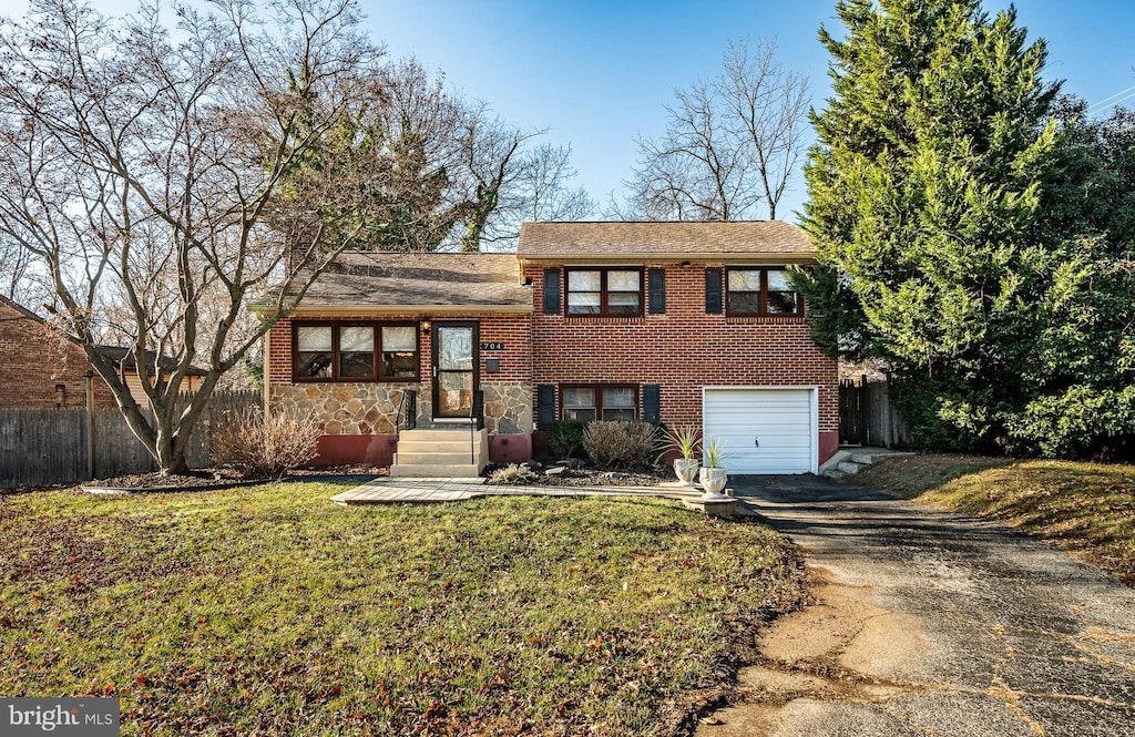 tri-level home featuring a garage and a front lawn