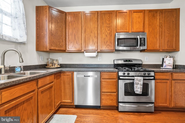 kitchen with appliances with stainless steel finishes, a sink, and brown cabinets