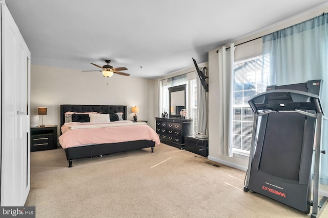 bedroom with ceiling fan, baseboards, visible vents, and light colored carpet