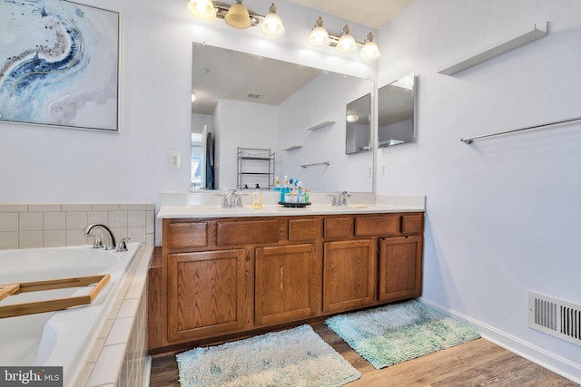 full bath featuring a garden tub, visible vents, a sink, and wood finished floors