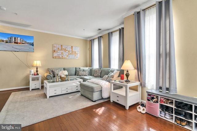 living area featuring ornamental molding, wood-type flooring, visible vents, and baseboards