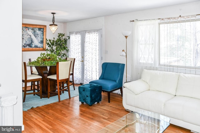 living room with wood-type flooring, french doors, an inviting chandelier, and plenty of natural light