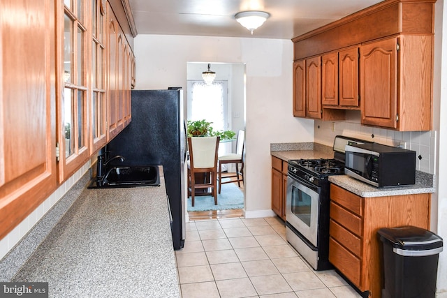 kitchen with backsplash, sink, light tile patterned flooring, and appliances with stainless steel finishes