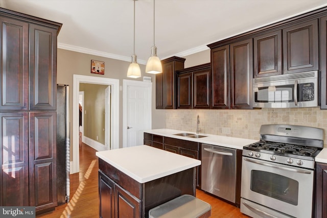 kitchen with stainless steel appliances, sink, decorative light fixtures, a center island, and crown molding