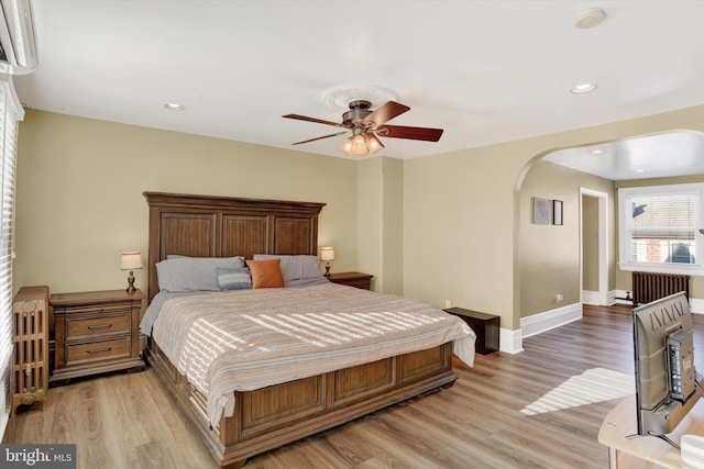 bedroom with ceiling fan, radiator, and light hardwood / wood-style flooring