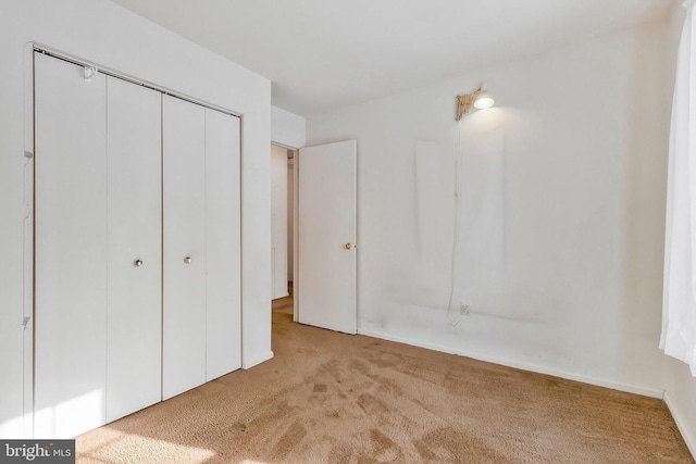 unfurnished bedroom with light colored carpet and a closet