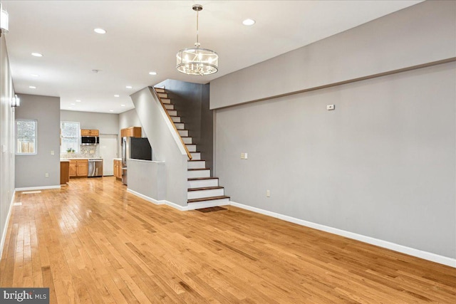 unfurnished living room featuring a chandelier and light wood-type flooring