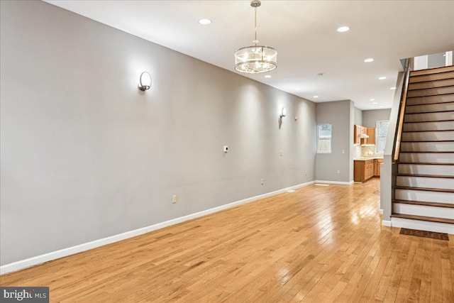 unfurnished living room featuring light wood-type flooring and an inviting chandelier