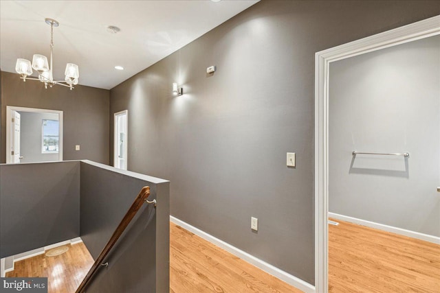 hall featuring light wood-type flooring and a chandelier