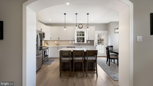 kitchen with wood-type flooring, a center island, decorative light fixtures, and white cabinetry