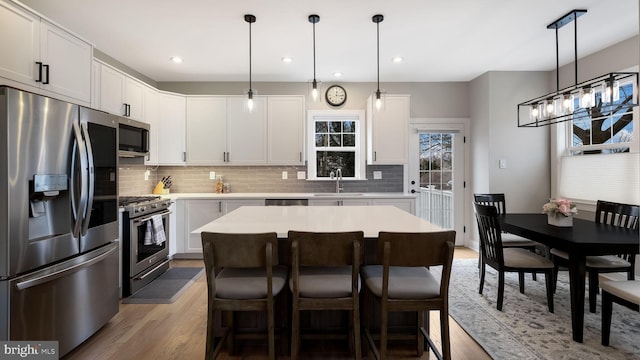 kitchen featuring white cabinets, pendant lighting, a center island, and stainless steel appliances