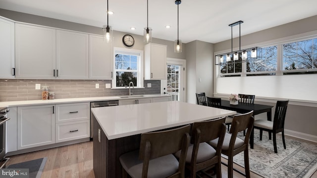 kitchen with white cabinets, a center island, sink, and pendant lighting