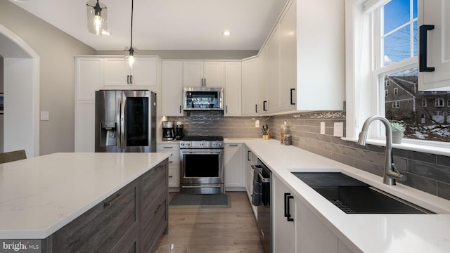 kitchen featuring pendant lighting, white cabinets, sink, light stone countertops, and stainless steel appliances