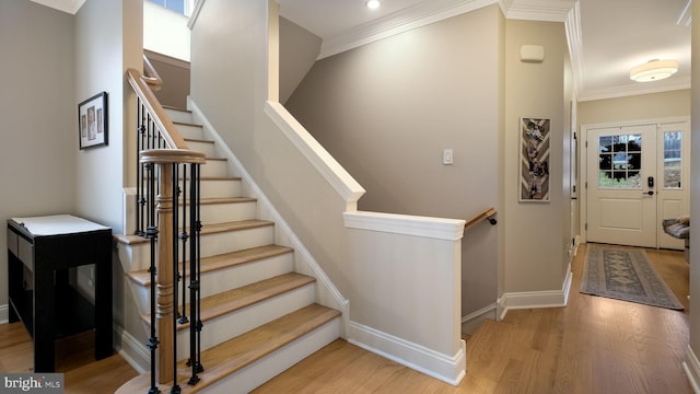 stairway featuring plenty of natural light, wood-type flooring, and crown molding