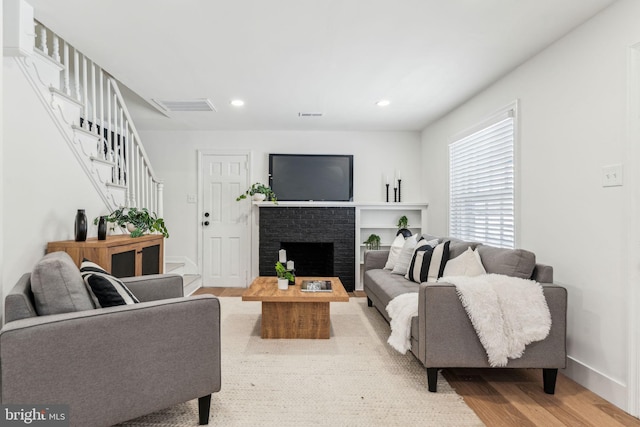 living room with a brick fireplace and hardwood / wood-style floors