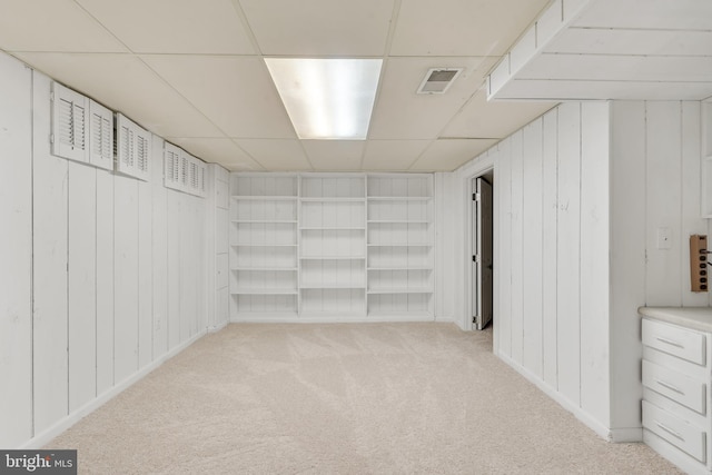 basement featuring a paneled ceiling and light carpet