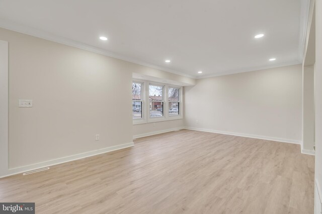 empty room with light wood-type flooring and crown molding