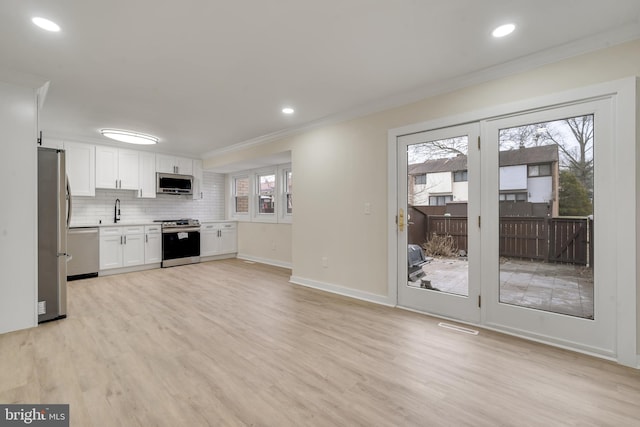 kitchen featuring light hardwood / wood-style floors, crown molding, backsplash, white cabinets, and appliances with stainless steel finishes