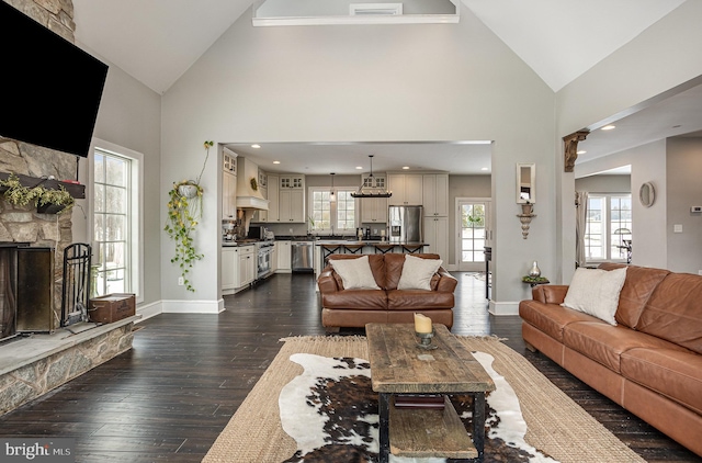 living room with a fireplace, dark hardwood / wood-style flooring, high vaulted ceiling, and a wealth of natural light